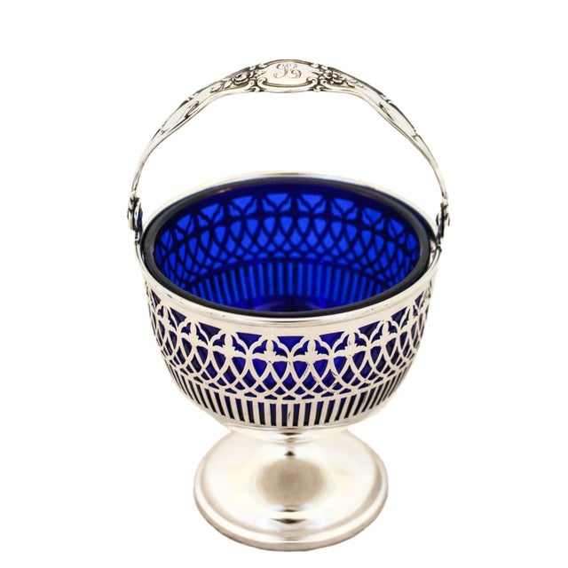 A beautiful sterling silver basket with a cobalt blue liner by Graff, Washbourne & Dunn. Standing proudly on a pedestal —...