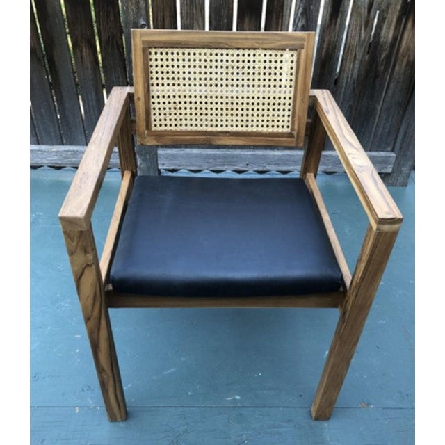 This pair of Coastal Boho accent dining armchairs features a solid teak wood frame with a caned back and leather cushion...