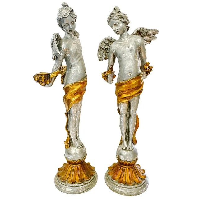 A fantastic pair of extra tall Revival winged putti candlestick holders in a lavish Baroque style. Each winged putti...