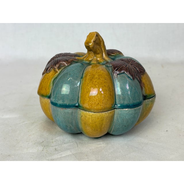 This gorgeous ceramic box is blue and gold with three brown leaves on top. It's deeply fluted with a handle convincingly...