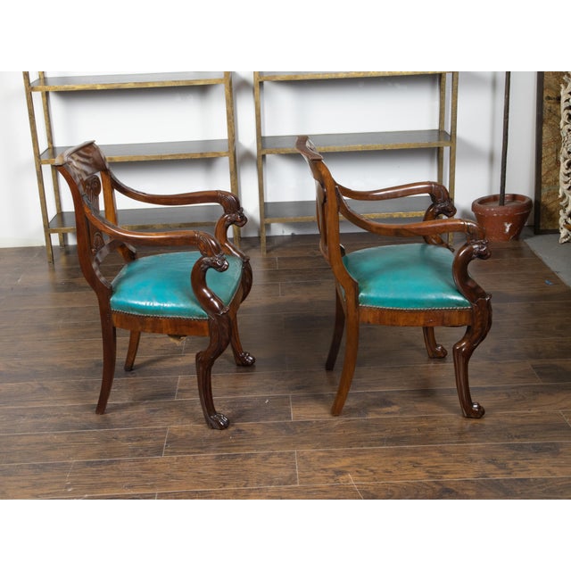 A pair of English Regency period mahogany armchairs from the mid 19th century, with ionic capitals, griffon arms and paw...