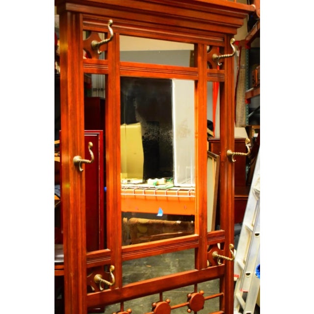 The design of the hall tree suggests a blend of functionality and decorative art, making it both a practical piece for...