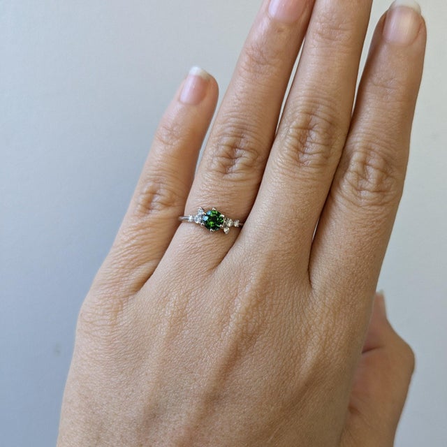 A green tourmaline takes centre stage in a fresh green at the heart of this solid 14K white gold ring, framed by six...