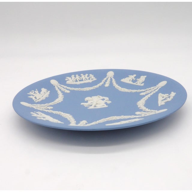A vintage Wedgwood pale blue Jasperware decorative plate, made in England. The "Cupid Stringing His Bow" pattern features...