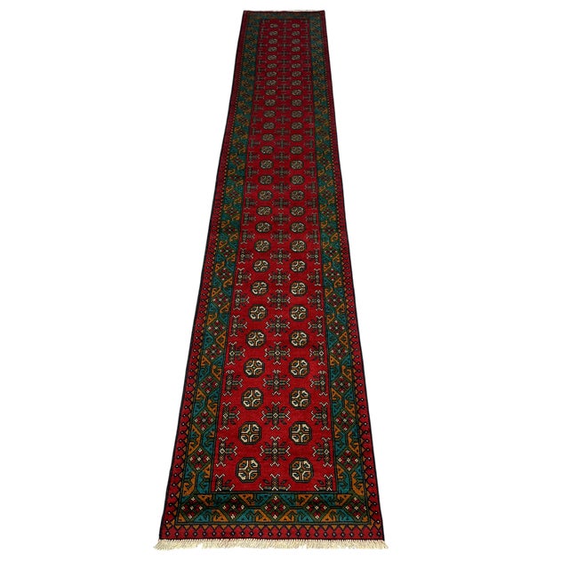This extra-long Turkmen tribal wool runner features a rich red field with two rows of repeating octagonal motifs....