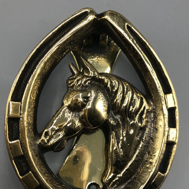 A circa 1930's English brass equestrian horse door knocker. It is solid brass and has a horse shoe surround. It is...