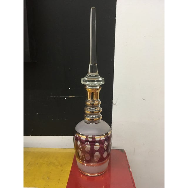 Vintage decanter in clear cranberry and gold accents. Tall hand cut stopper.