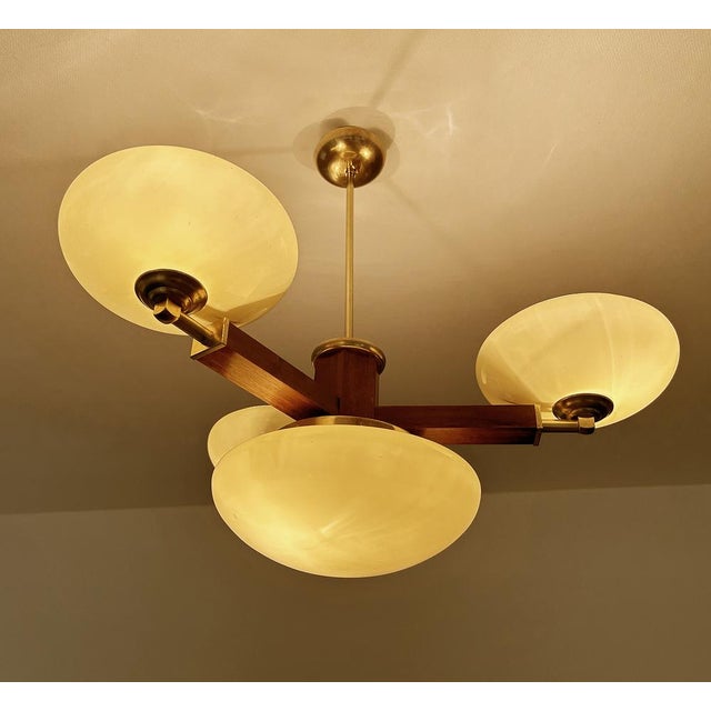Large Art Deco pendant light featuring a wood structure with brass and trim, large central glass shade mounted on a brass...