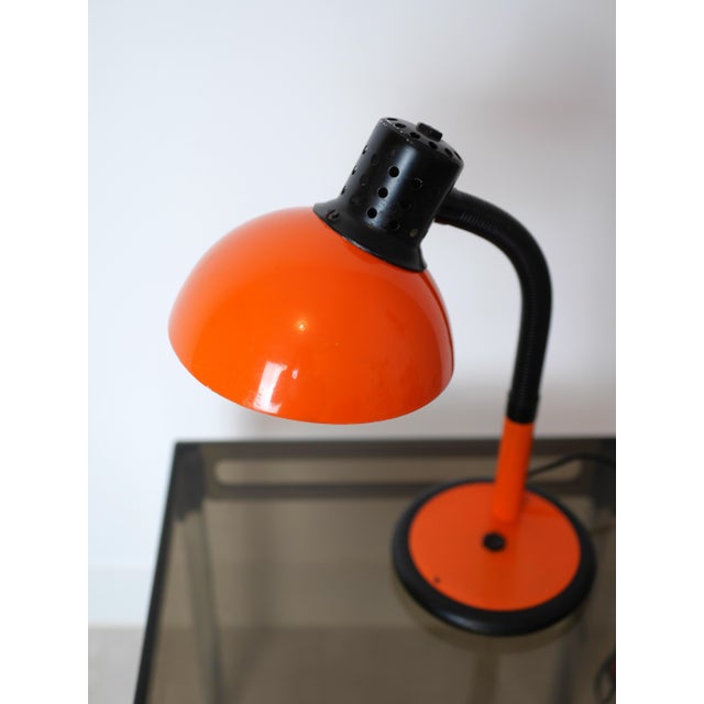 Orange Aluminor desk lamp. Dating from the 1970s-80s, this model features a flexible black arm for adjustable positioning....
