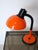 Orange Aluminor desk lamp. Dating from the 1970s-80s, this model features a flexible black arm for adjustable positioning....