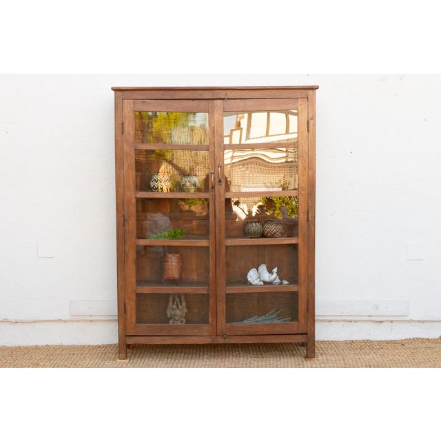 This 65-inch tall cabinet is a classic example of British Colonial utility furniture, crafted from solid teak. It features...