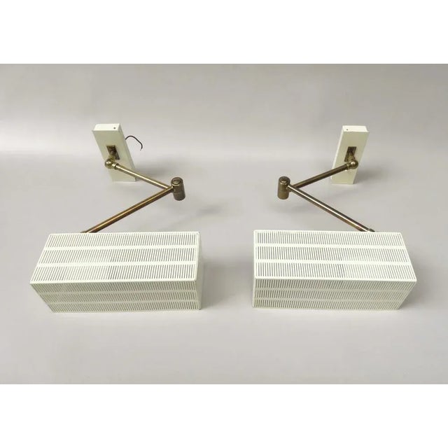 A pair of wall lights, "cube", from the 1960s in the rare and elegant combination of beige and brass. The manufacturer is...