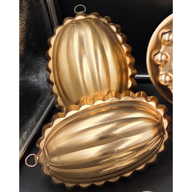 ​An extensive, highly curated collection of 17 vintage kitchen molds, featuring a stunning array of metallic copper-toned...