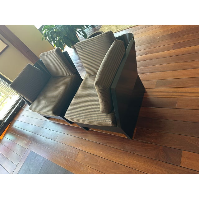 This pair of Donghia armchairs features a sleek, architectural design with angular black frames and deep, tailored seats....