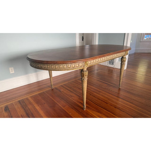 This exceptional antique dining table, likely from the 1910s–1920s, embodies neoclassical elegance with a richly figured...