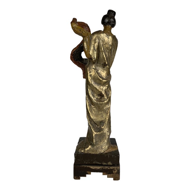 A vintage signed sculpture of an Asian woman. Her gold robe reflects light quite authentically.