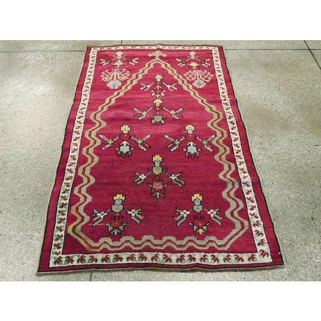 This early 20th century Turkish Ghiordes rug, measuring 3' 5" x 5' 2", features a striking tribal design infused with rich...