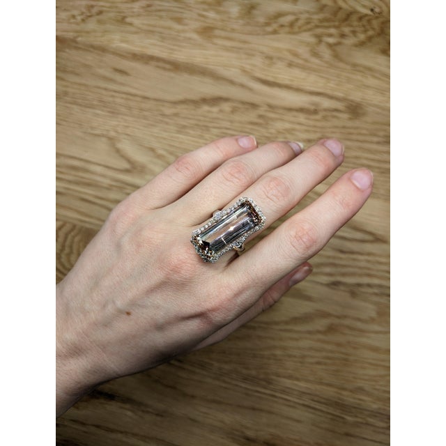 A pink tourmaline rests in a vibrant pink at the heart of this solid 14K white gold ring, encircled by thirty-six earth-...