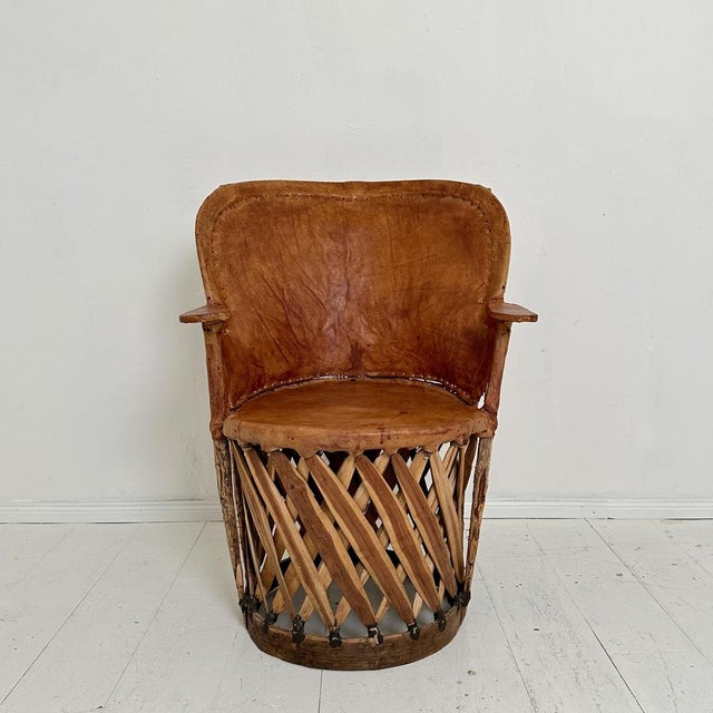 This mid-century Mexican Equipales armchair, crafted around 1970, exudes rustic charm. Its robust wooden frame provides a...