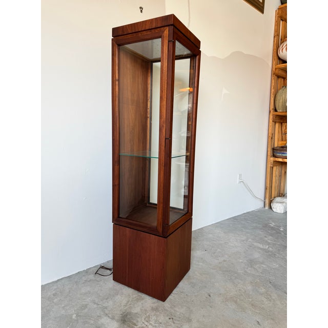 A refined 1970s Mid-Century Modern Danish display or curio cabinet featuring a rich walnut frame with clean, minimalist...