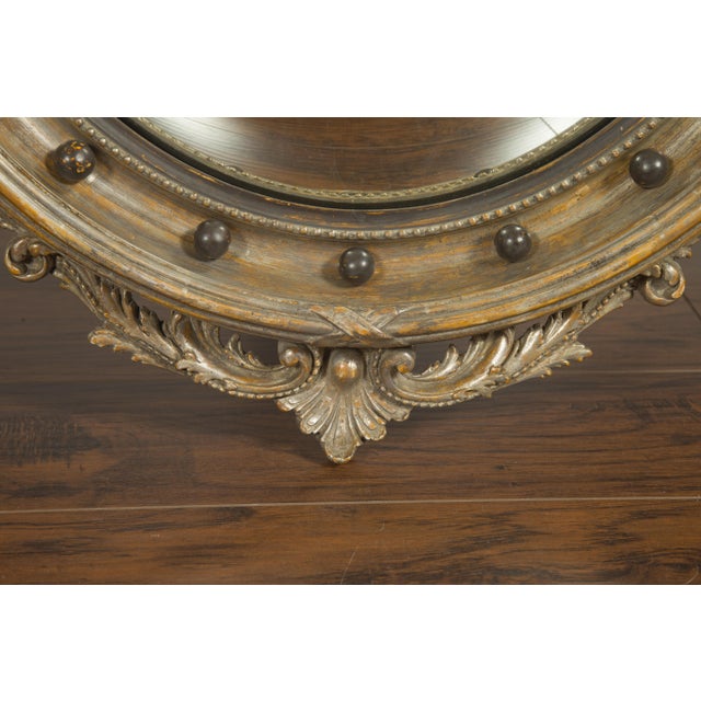 An English silver leaf convex girandole bullseye mirror from the early 20th century, with carved eagle motif and volutes....