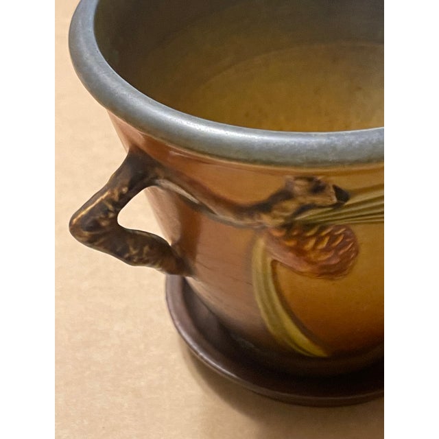 This beautiful Roseville Double Handled Pine Cone Flower Pot with Matching Saucer - presented in a stunning textured matte...