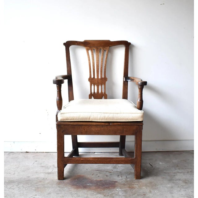 An early 18th-century, c. 1710-1720, Georgian armchair with a Chippendale splatted back, curved armrests, and turned...