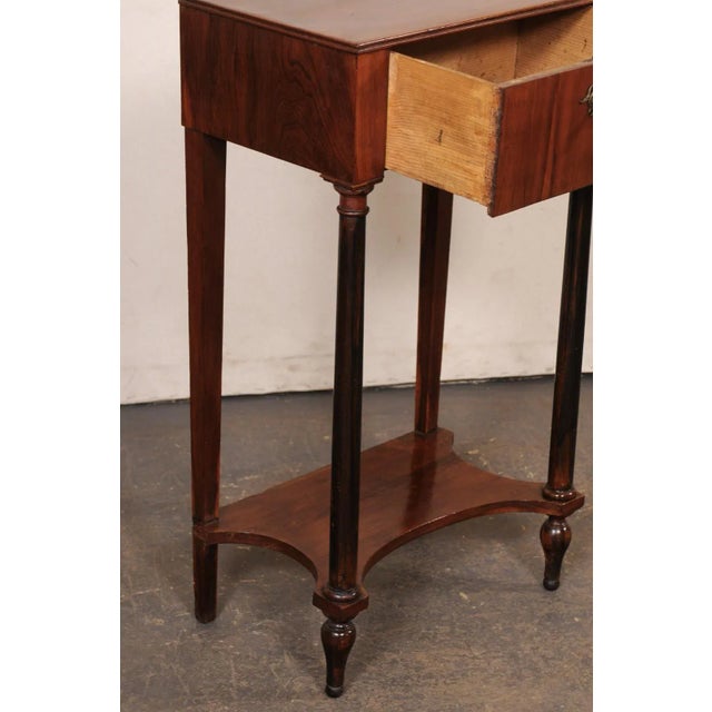 An Italian Neoclassical style end table, with drawer and lower secondary shelf, from the 19th century. This antique table...