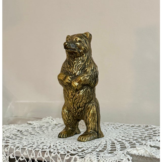 A vintage solid brass bear coin bank modeled in a classic standing pose. The figure is well sculpted with defined fur...