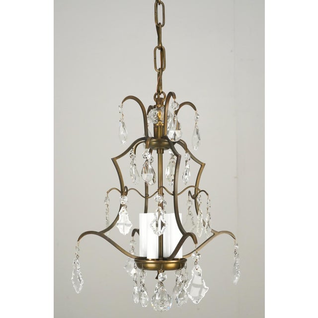 Victorian style brass crystal chandelier in a central cluster design with four curved arms. Faceted drop crystals hang...