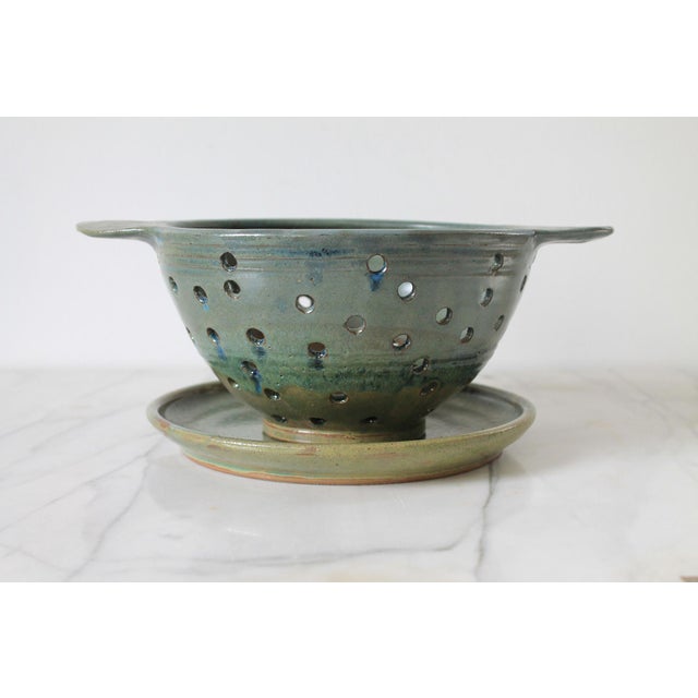 Vintage glazed studio art pottery berry strainer with handles and matching saucer. No makers mark. Minor age wear. No...
