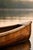 Minimalist lake artwork featuring a wooden canoe resting on calm water with soft reflections and warm, natural tones. The...