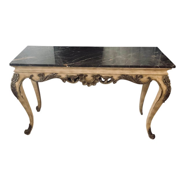This appears to be an elegant French Provincial/Louis XV-style console table or writing desk with a black marble top,...