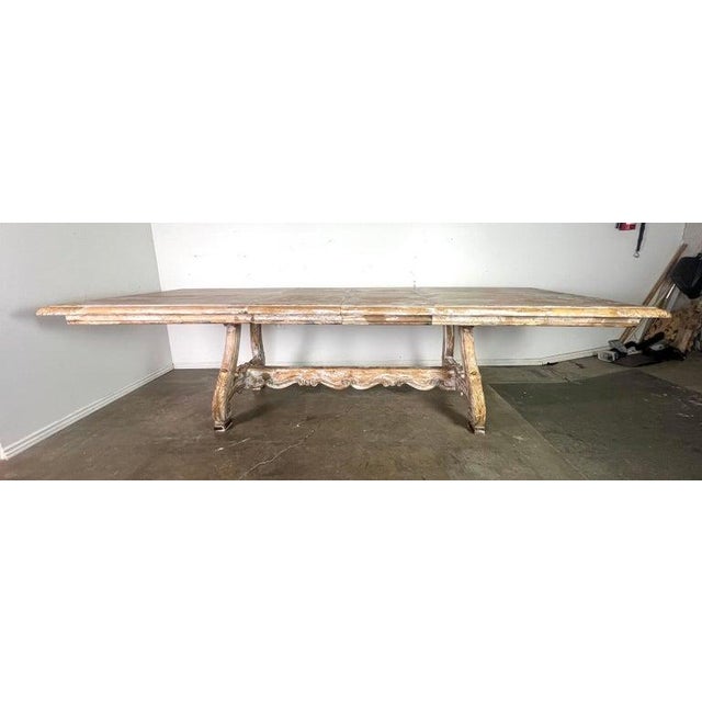 Italian carved wood painted trestle dining table with leaves. The table has a vintage, weathered look. It is made of wood...