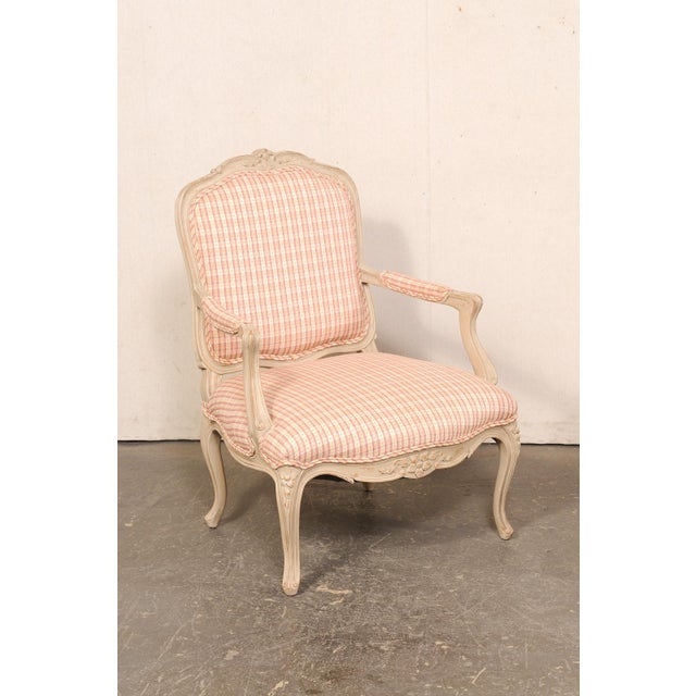 A French pair of carved-wood and upholstered Louis XV style armchairs from the mid 20th century. This vintage pair of...