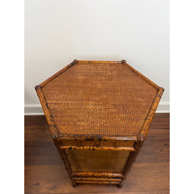 Vintage British Colonial Style Two Tier Hexagonal Side Table. Crafted from tortoise shell faux bamboo with rattan panels....