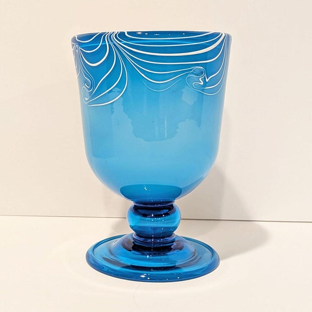 A striking hand-blown Murano art glass vase in a vivid aqua blue, featuring free-applied white trailed decoration in...