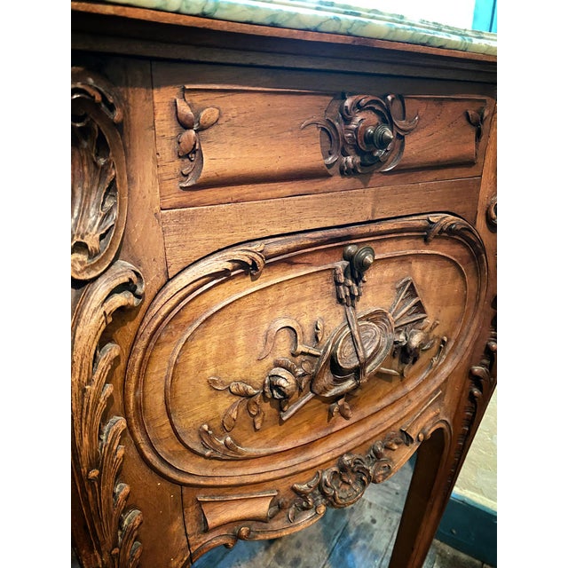 An elegant Louis XV style bedside table in carved walnut, made in the late 19th century. This charming piece rests on four...