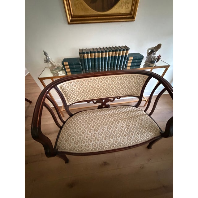 Elegant vintage Victorian-style settee featuring a beautifully shaped dark mahogany-toned wood frame with graceful curved...