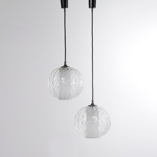 Pair of Italian-made pendant lamps from the 1960s. Double-glass diffuser: the first is a clear sphere with embossed...