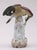 Dresden porcelain bird perched on a tree stump eating leaves painted in mauve, blue, black, cream and gray. Painted by...