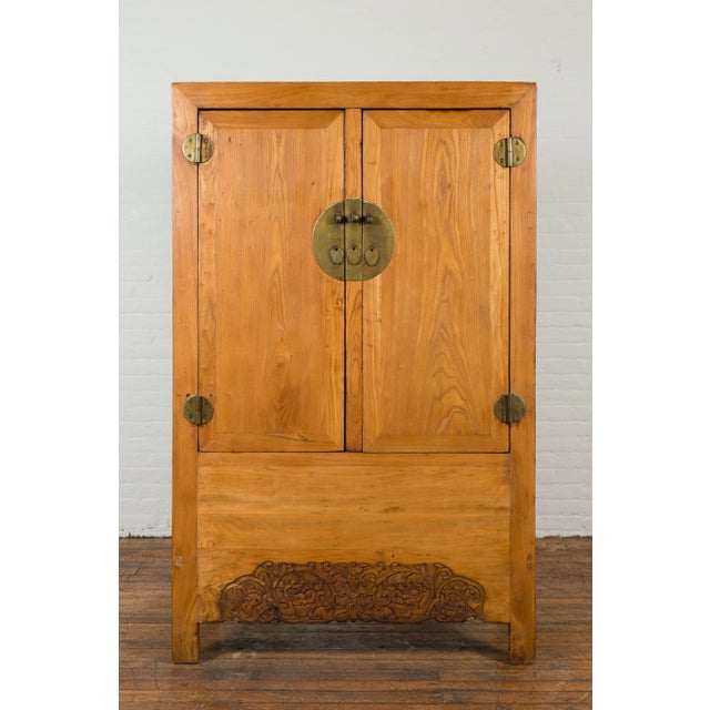 A Chinese vintage elmwood wedding cabinet from the mid 20th century, with carved apron, hidden drawers and brass hardware....