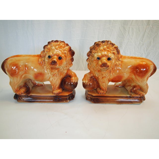 A well modeled and colorful pair of early 20th Century English Staffordshire Earthenware Lions. Stamped underneath...