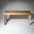 Long rectangular console table on straight stainless steel legs with decorative profiling. The top is covered in beige...