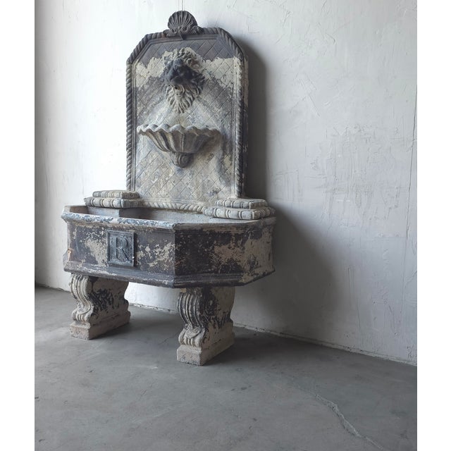 This is a beautifully weathered European style, cast stone wall fountain featuring a lion's head spout, shell-form basin,...