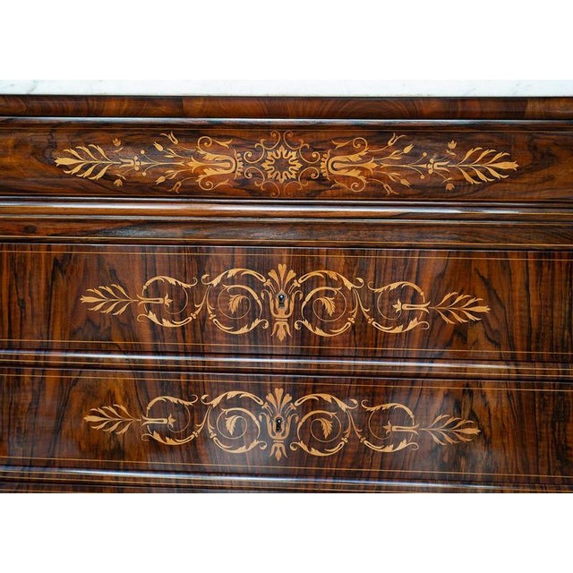Antique Charles X French chest of drawers in walnut burl with maple inlays and a marble top. The front is punctuated by...