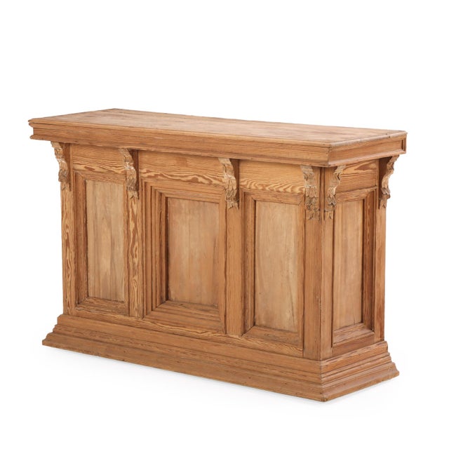 A handsome French pine bar counter featuring a wood top, carved corbels, and paneled details along the front and sides....