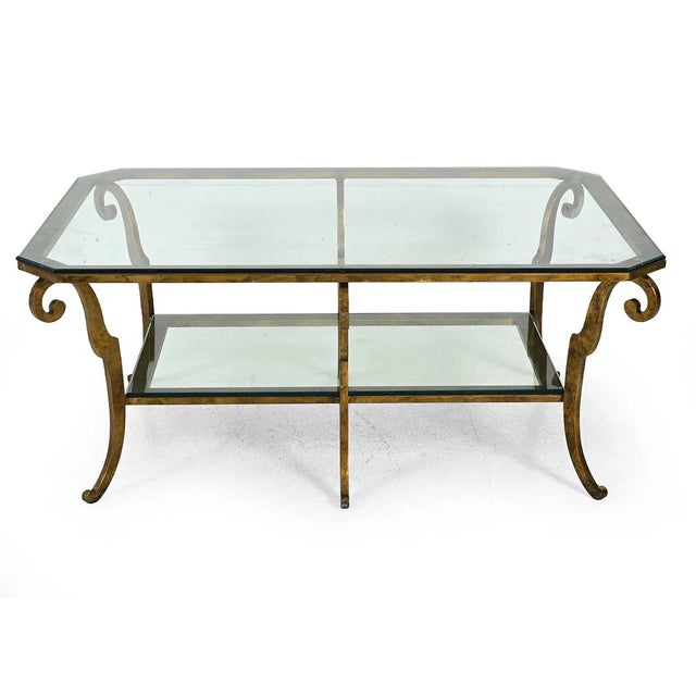 An impressive oversized vintage coffee table featuring a gilt iron frame with elegant scrollwork, curved legs, and two...