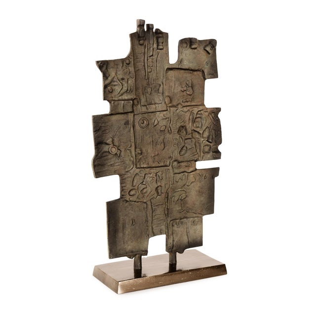 This abstract sculpture features a geometric block design with intricate carved textures and a hand-applied bronze finish....