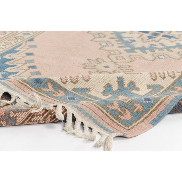 This is a vintage Turkish Oushak rug from the Mid 20th Century. The piece was hand-knotted.